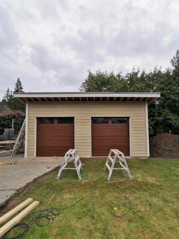 Finished detached garage with two brown doors and beige siding