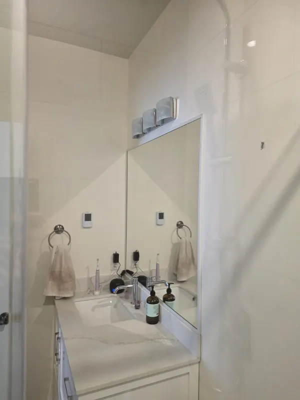 Bathroom with a white vanity, mirror and tiled walls