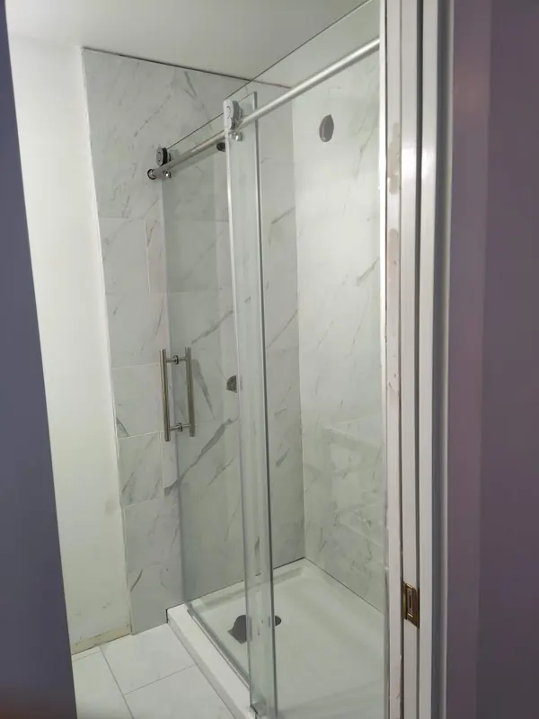 Marble-look tiled shower with a sliding glass door