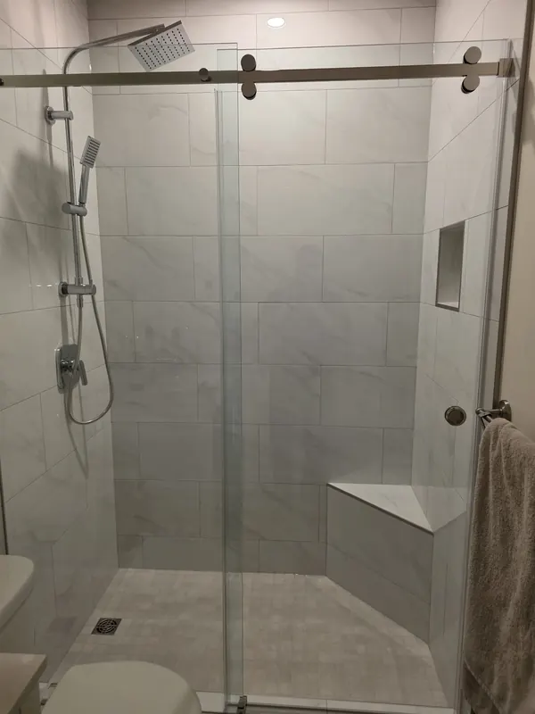 Tiled walk-in shower with a built-in bench, niche and sliding glass door