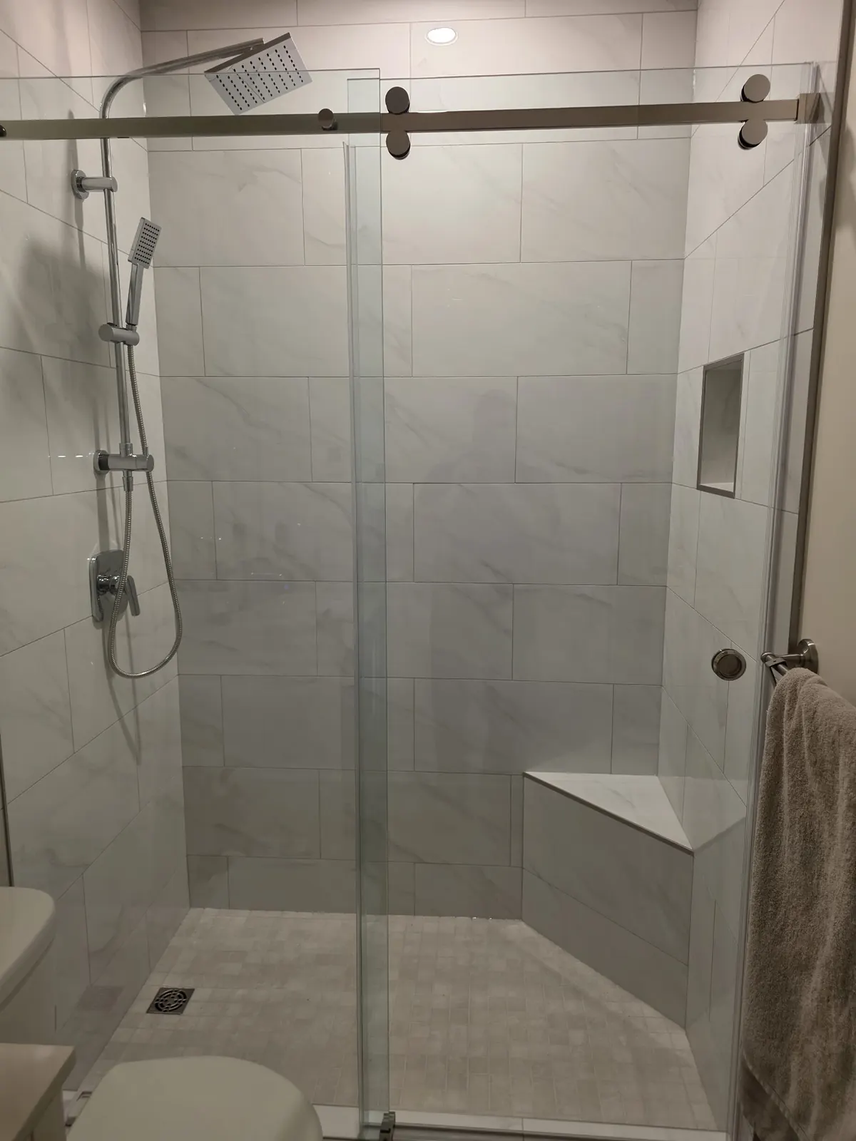 Tiled walk-in shower with a built-in bench, niche and sliding glass door