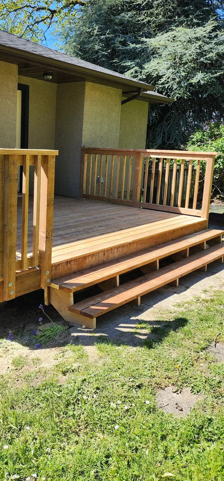 New cedar deck with cedar railing and wide steps on a stucco cottage