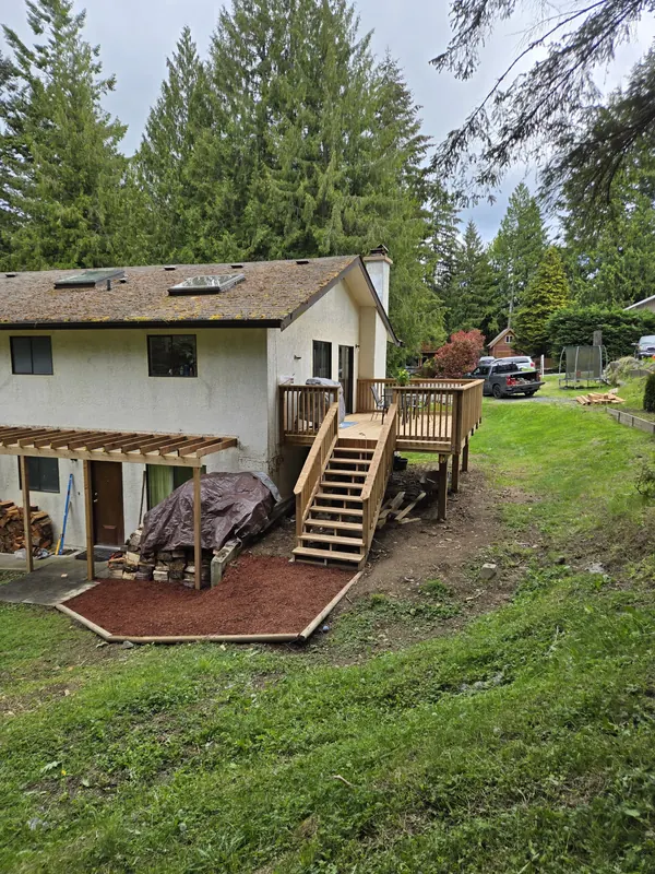 Cedar deck with stairs and a pergola beside a stucco house
