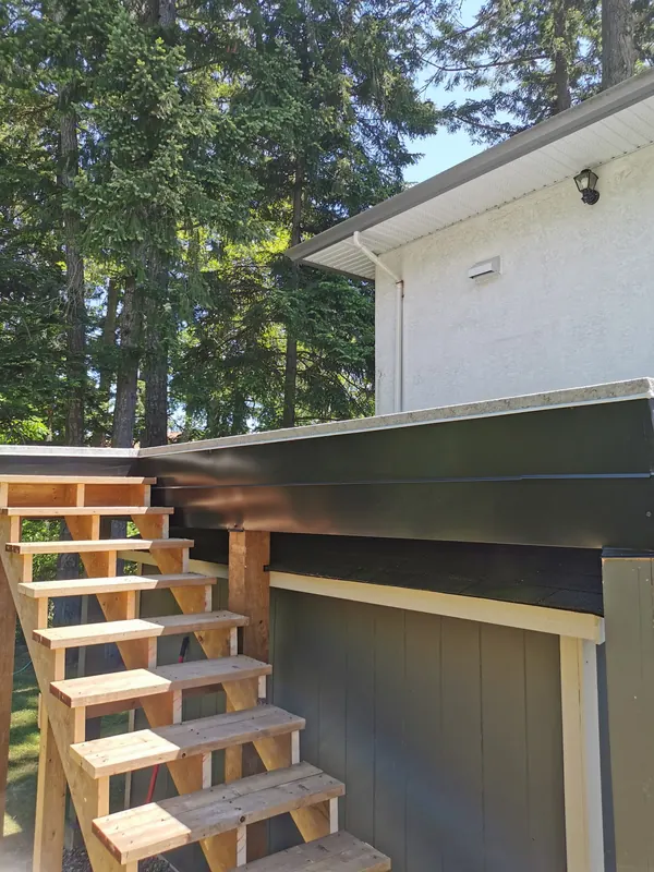New cedar stairs climbing beside a dark-clad house