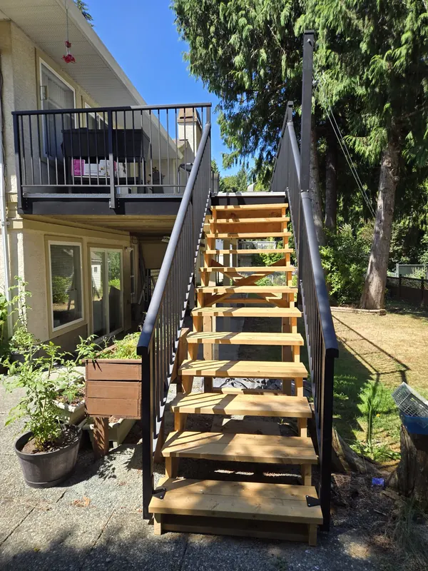 New cedar stairs with black aluminum railings up to an upper deck