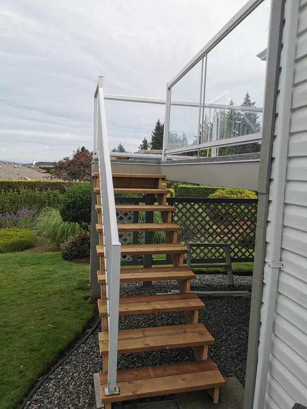 New cedar stairs with a white aluminum rail up to a glass-railed deck