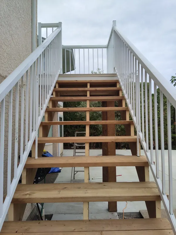 New cedar stairs with white aluminum railings leading to an upper deck