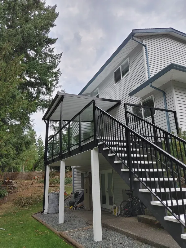 Elevated deck with black glass railing and a black stair run on white posts