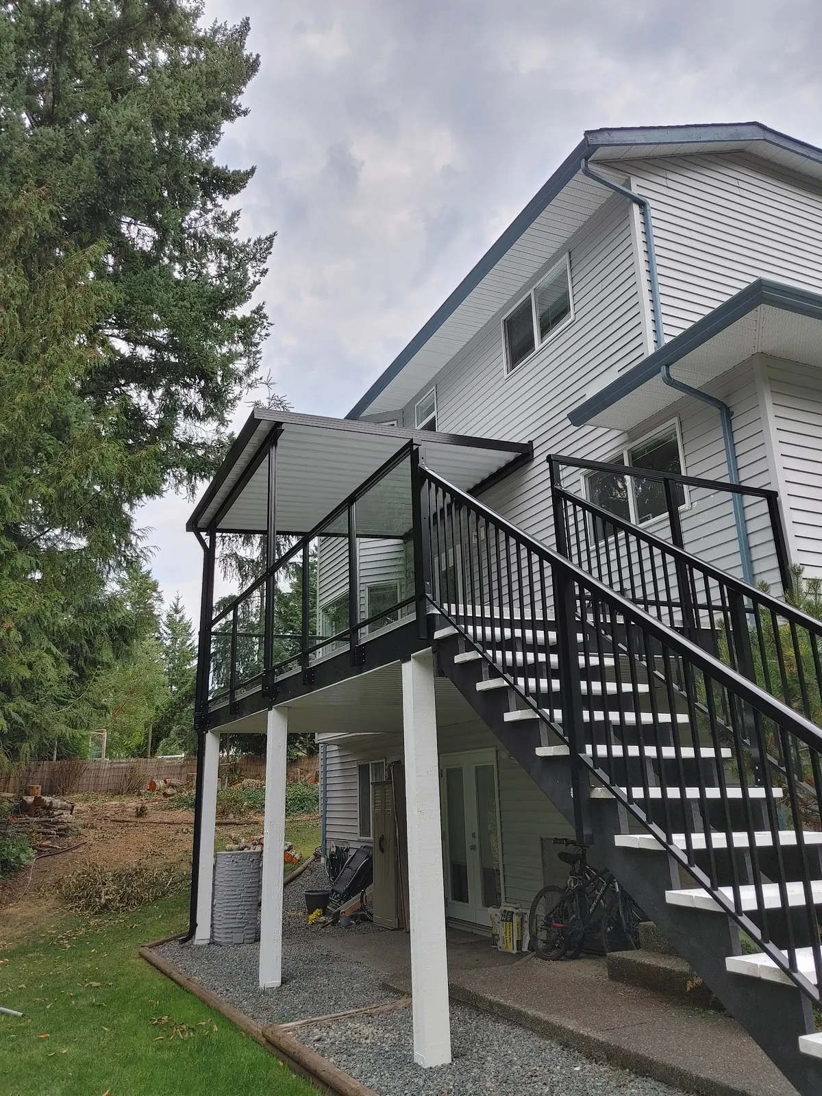 Elevated deck with black glass railing and a black stair run on white posts