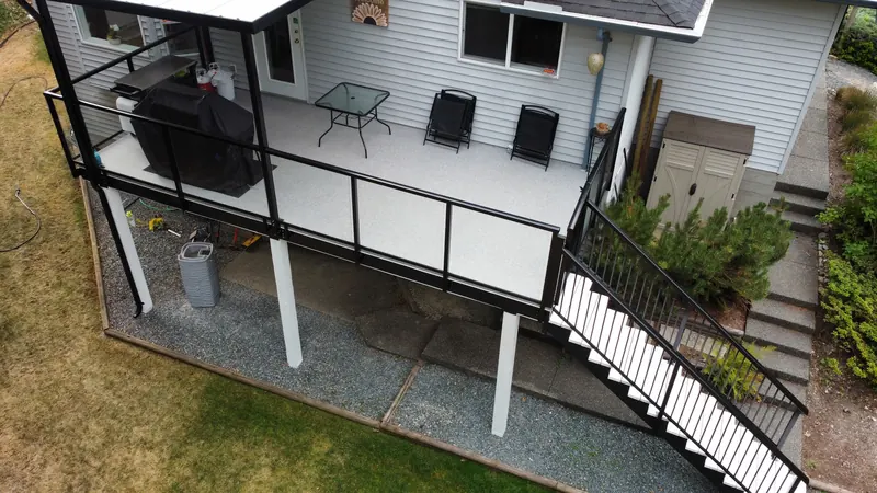 Aerial view of an elevated deck with black railing and an awning over the patio