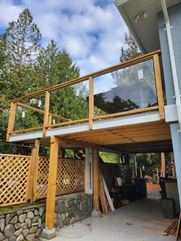 Elevated deck with cedar and glass railing over a lattice-skirted stone base