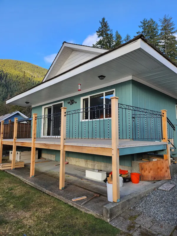 New cedar-framed deck with a black metal railing on a teal cottage