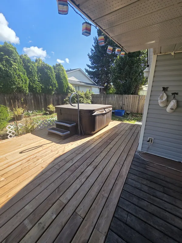 Deck re-boarding in progress beside weathered boards and a hot tub