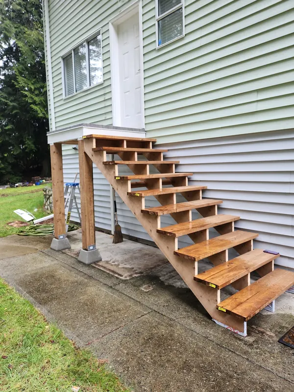 Rebuilt cedar stairs and landing on a green-sided house