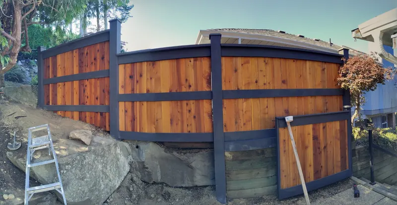 Cedar privacy fence with a dark steel frame on a rocky lot
