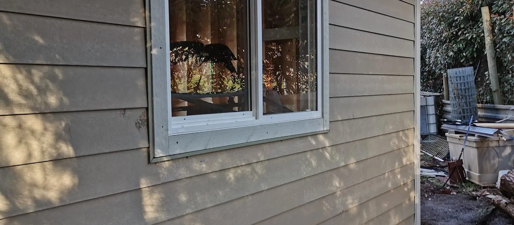 Beige lap siding on a garage with a white-trimmed window
