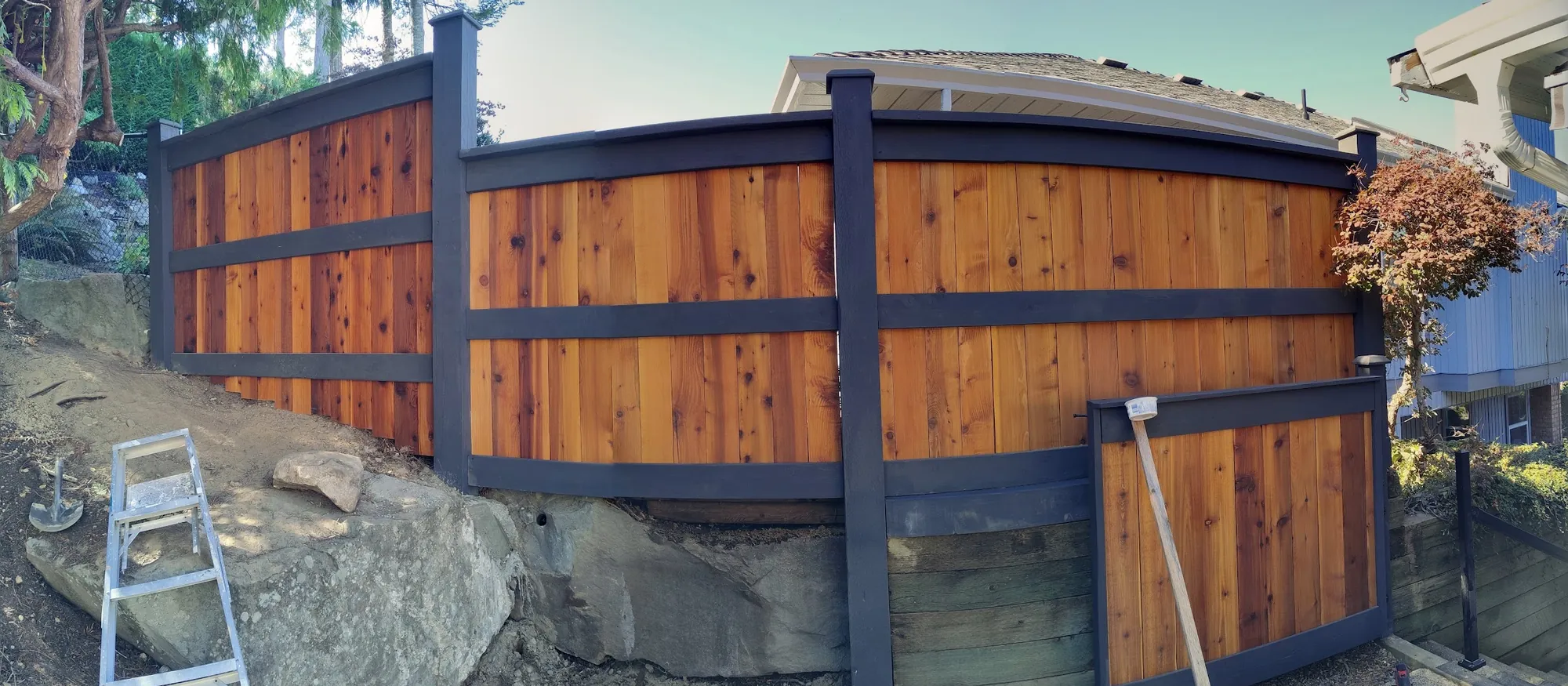 Cedar privacy fence with a dark steel frame on a rocky lot