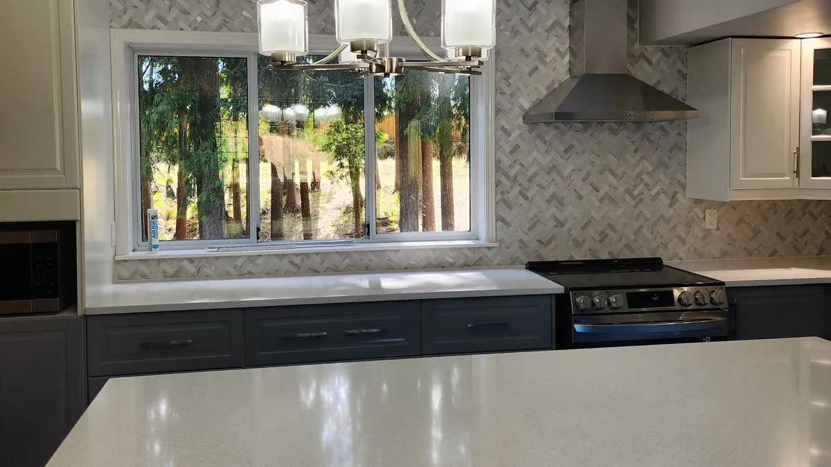 Kitchen with a navy island, white cabinets and a chandelier