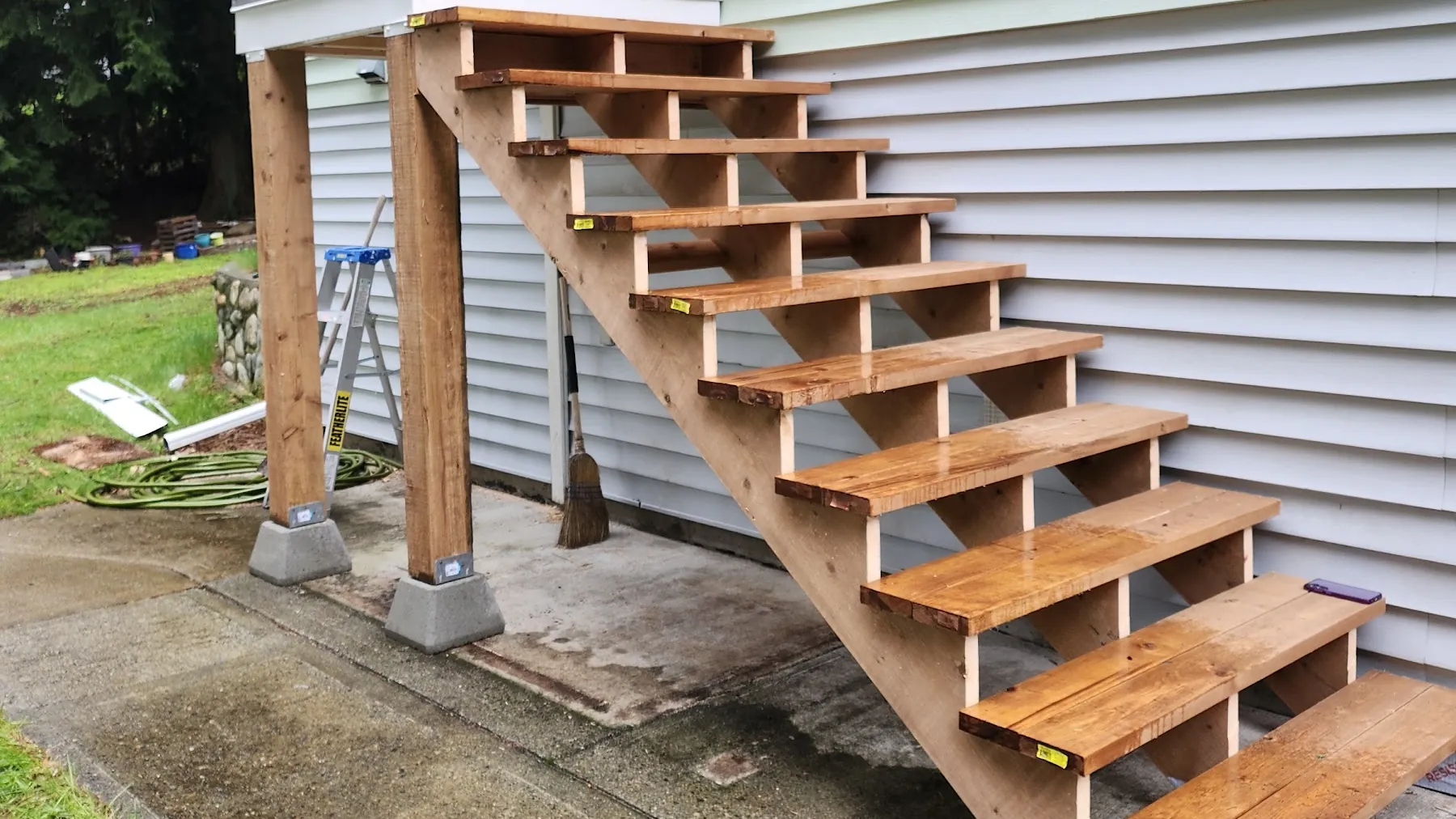 Rebuilt cedar stairs and landing on a green-sided house