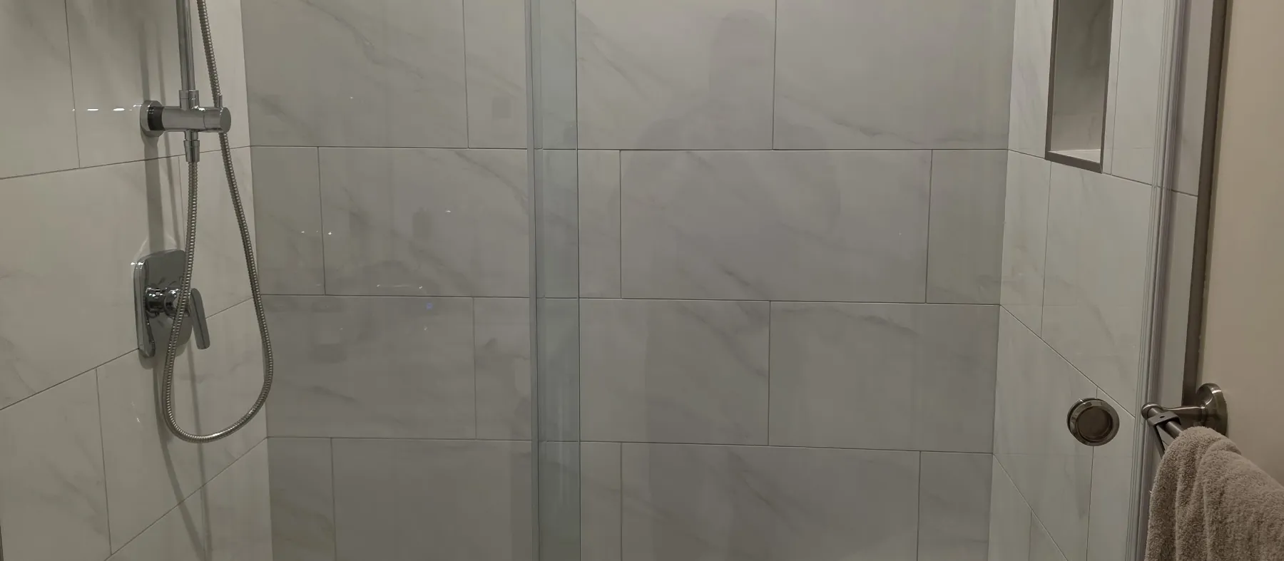 Tiled walk-in shower with a built-in bench, niche and sliding glass door