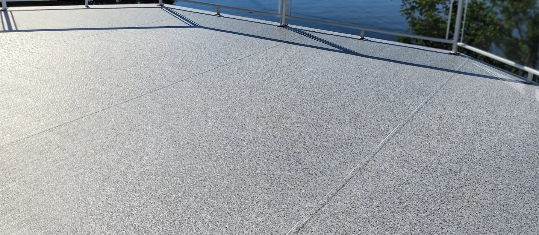 Light speckled vinyl deck with a white aluminum and glass railing overlooking the ocean