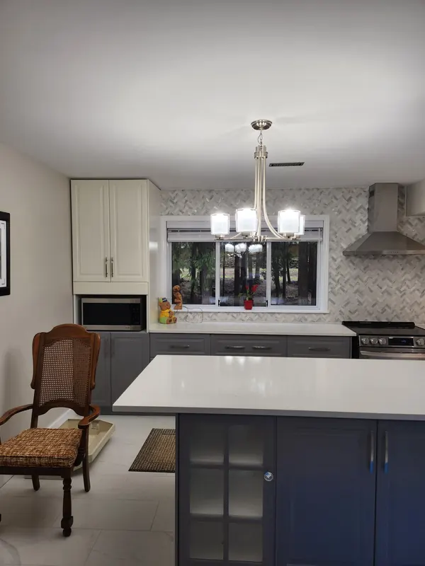 Finished kitchen with a navy island, white cabinets and a large-format tile floor