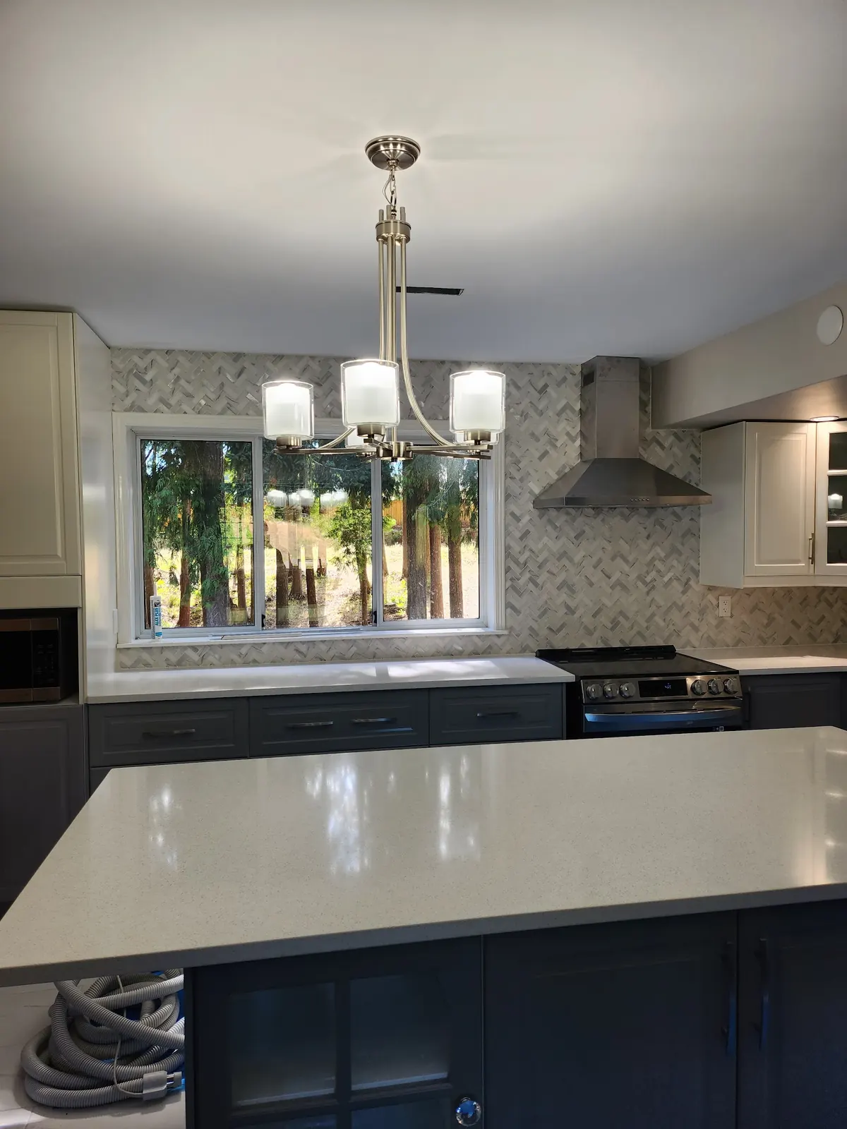 Kitchen with a navy island, white cabinets and a chandelier
