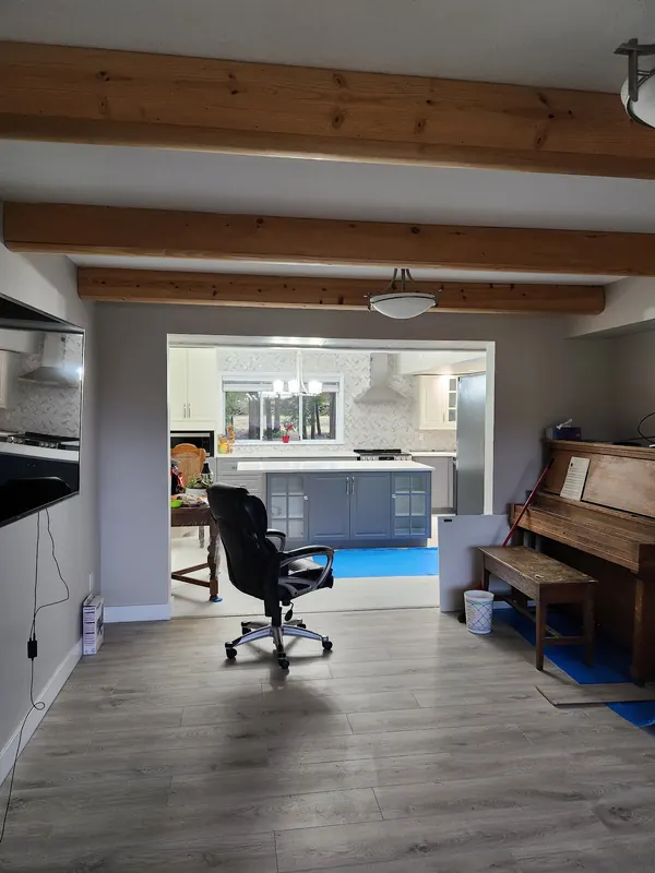 Open living space with exposed beams and new grey plank flooring