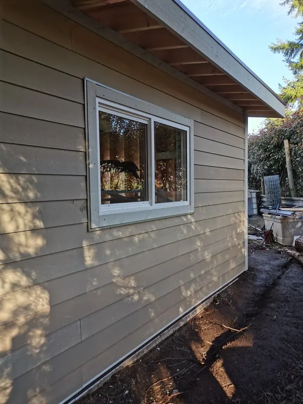 Beige lap siding on a garage with a white-trimmed window