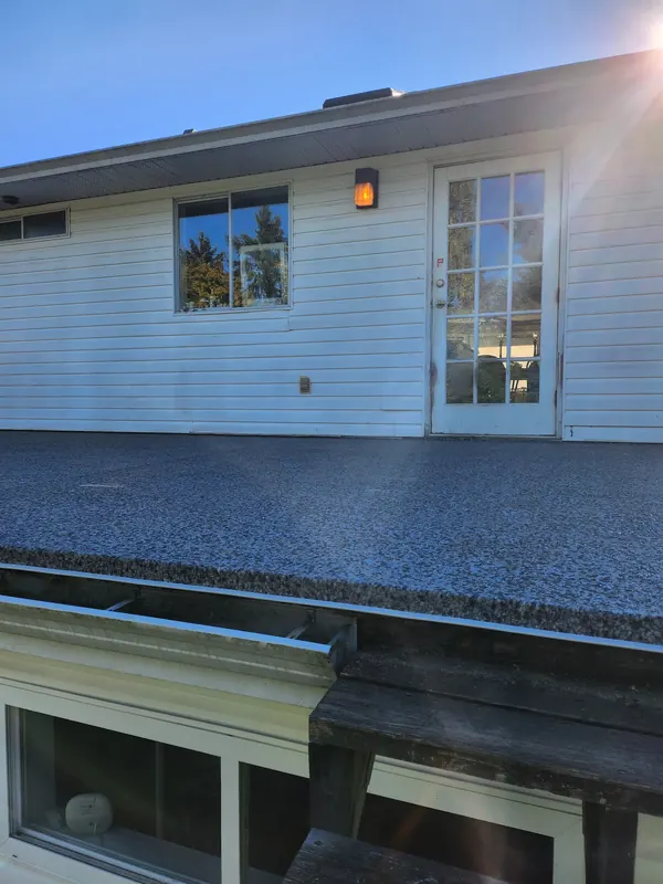 Speckled vinyl membrane on a porch roof outside a French door, sealed up to the house wall