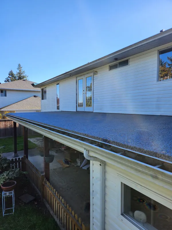Speckled vinyl membrane on a flat porch roof, waterproofing the covered patio below