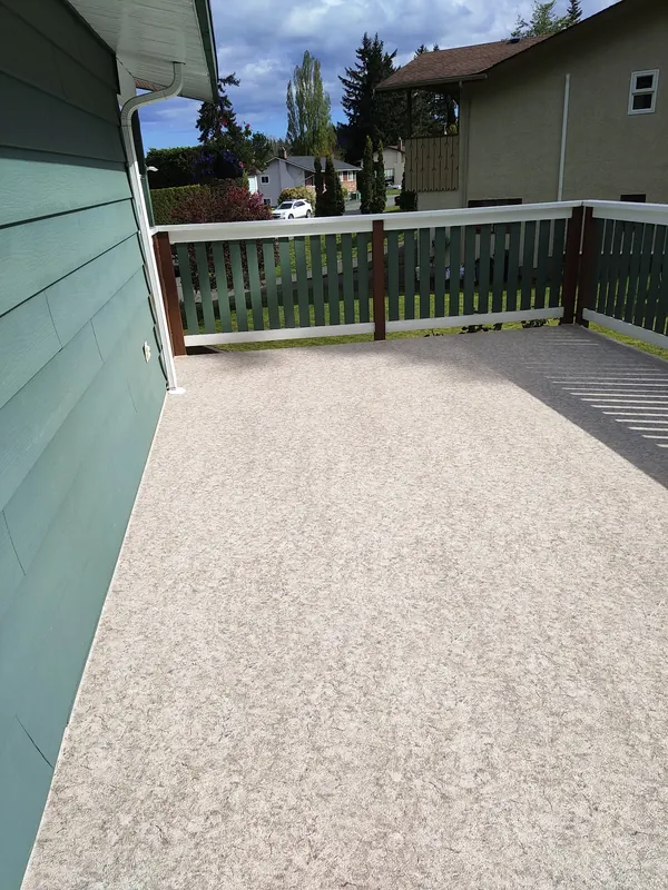 Beige speckled vinyl deck with a green picket railing and white top rail