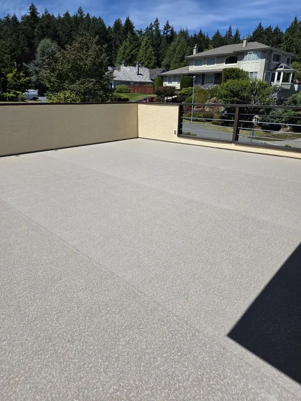 Light beige vinyl deck surface inside a stucco parapet with a metal rail