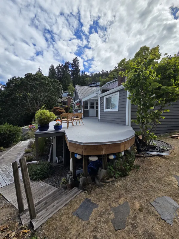 Curved vinyl-surfaced deck with cedar fascia beside a cottage