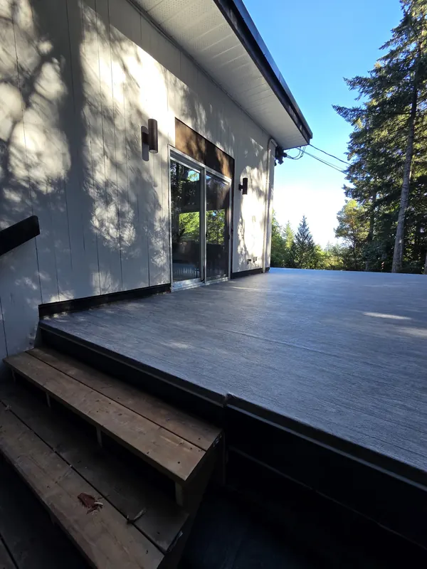 Dark wood-grain vinyl deck at a modern house with cedar steps