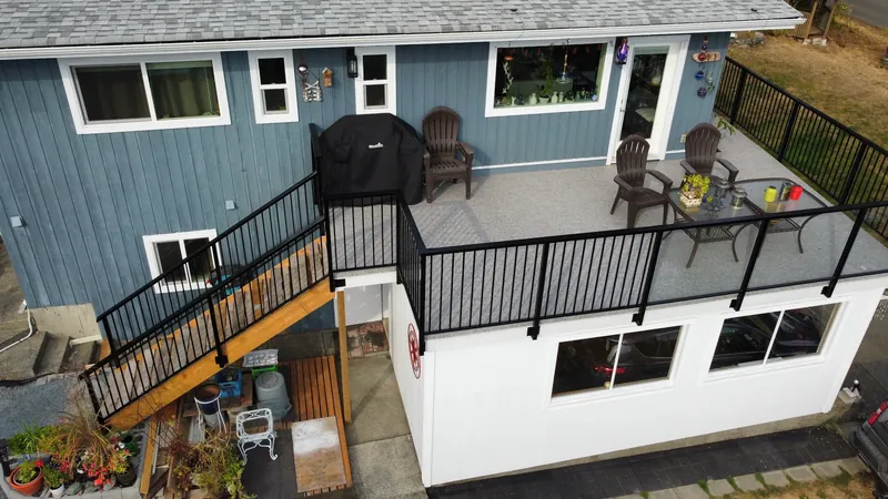 Drone view of an elevated vinyl deck with a black aluminum railing and cedar stairs