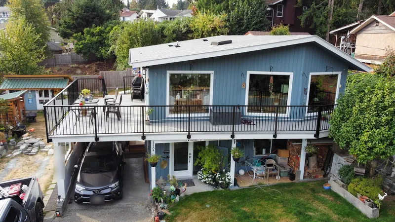 Drone view of a long vinyl deck over a carport on a blue house, black railing all around