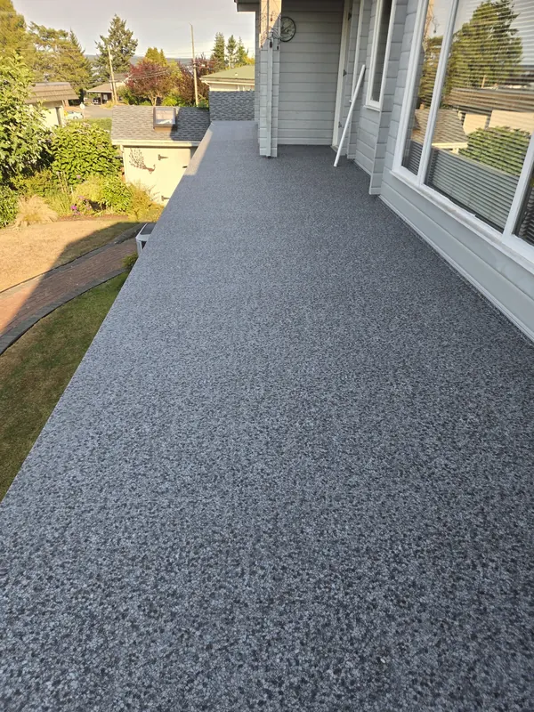 Long granite-flake vinyl deck running along the side of a white house