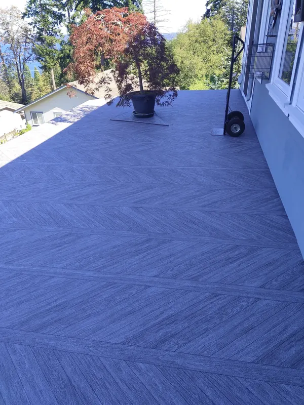 Blue-grey herringbone-pattern vinyl deck beside the house with a potted tree