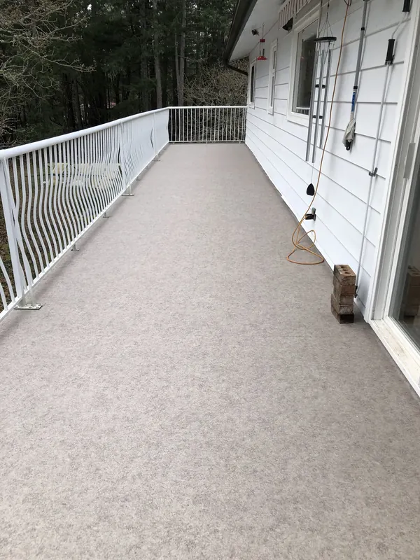 Long beige vinyl deck with a white curved-picket railing along the side of a house