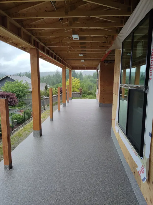 Long grey speckled vinyl deck under a covered roof with cedar posts