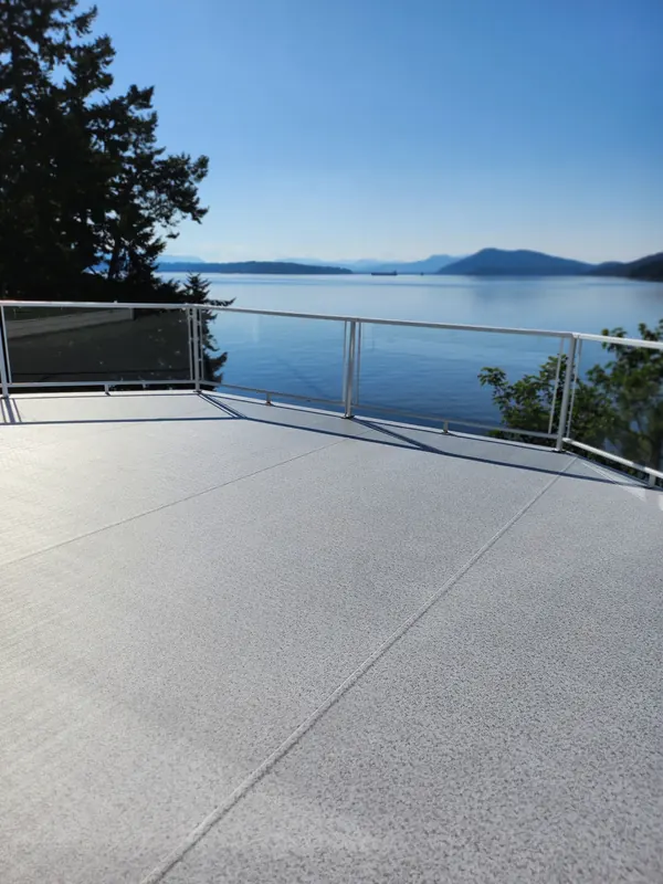 Light speckled vinyl deck with a white aluminum and glass railing overlooking the ocean