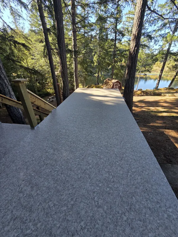 Finished speckled vinyl deck with a lake view through the trees
