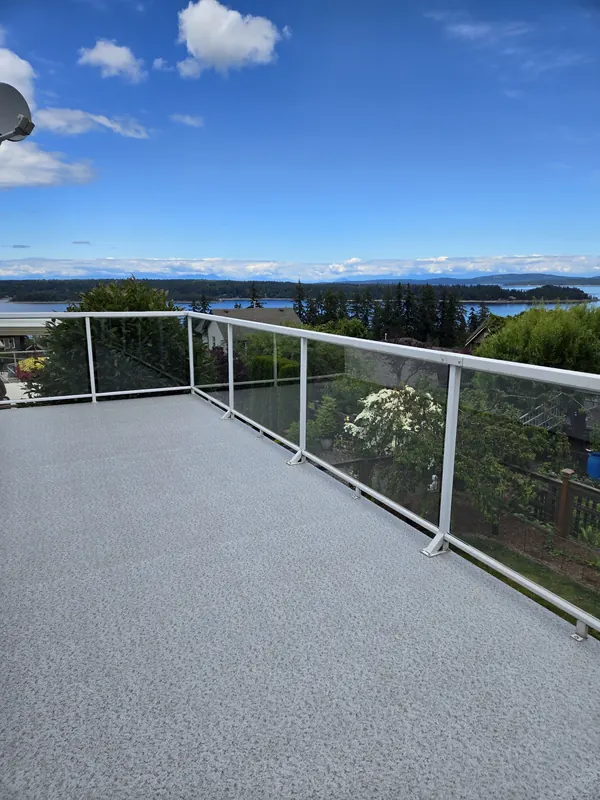 Large light vinyl deck with white aluminum glass railing and a view over the water to the islands