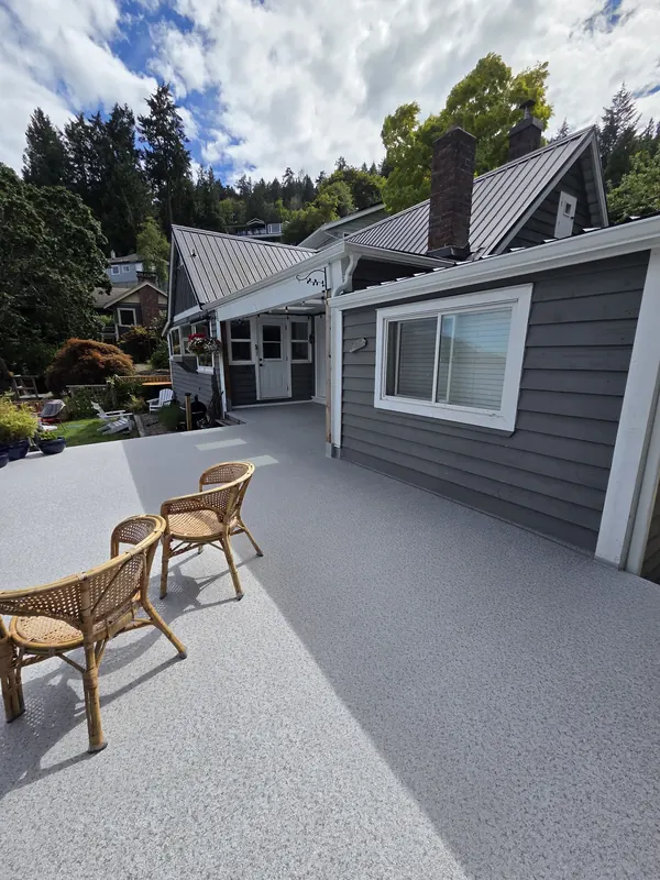 Light speckled vinyl deck with wicker chairs beside a waterfront cottage