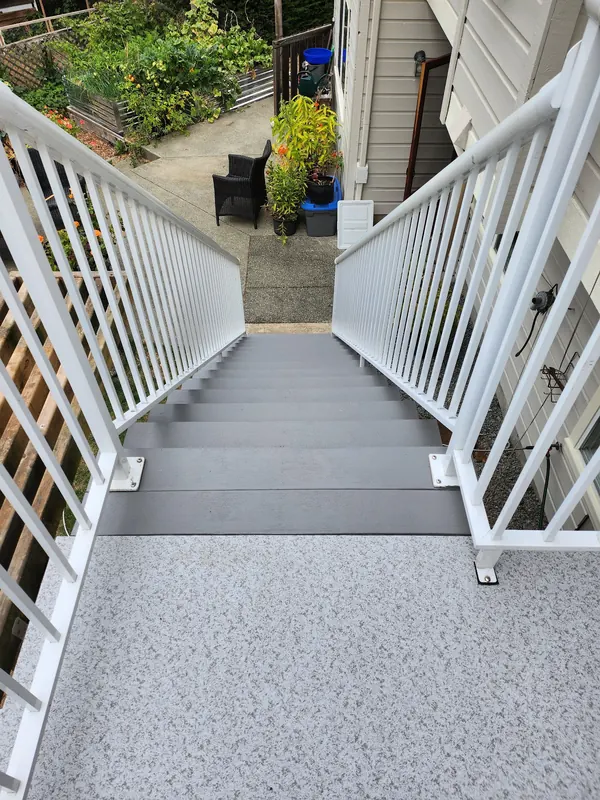 Vinyl-surfaced landing and grey stair treads between white aluminum railings